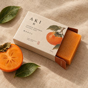 The bar sliding out of its box beside a halved persimmon